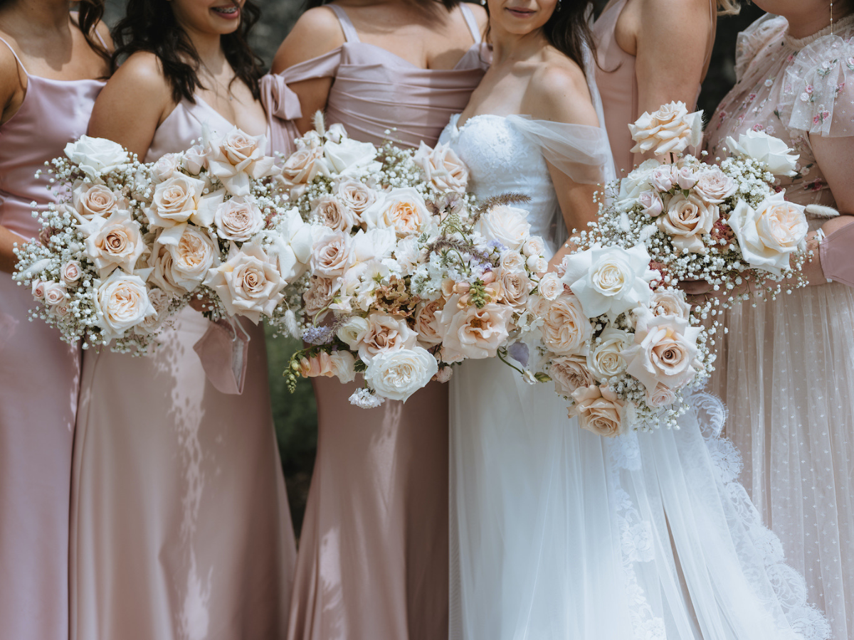 Bride and bridesmaids holding their blush, white and baby's breath bouquets with hints of lilac at Elora Mill