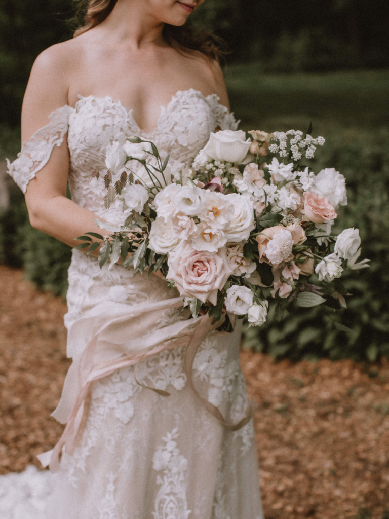 Bride holding her bridal bouquet made up of lots of blush and white toned florals