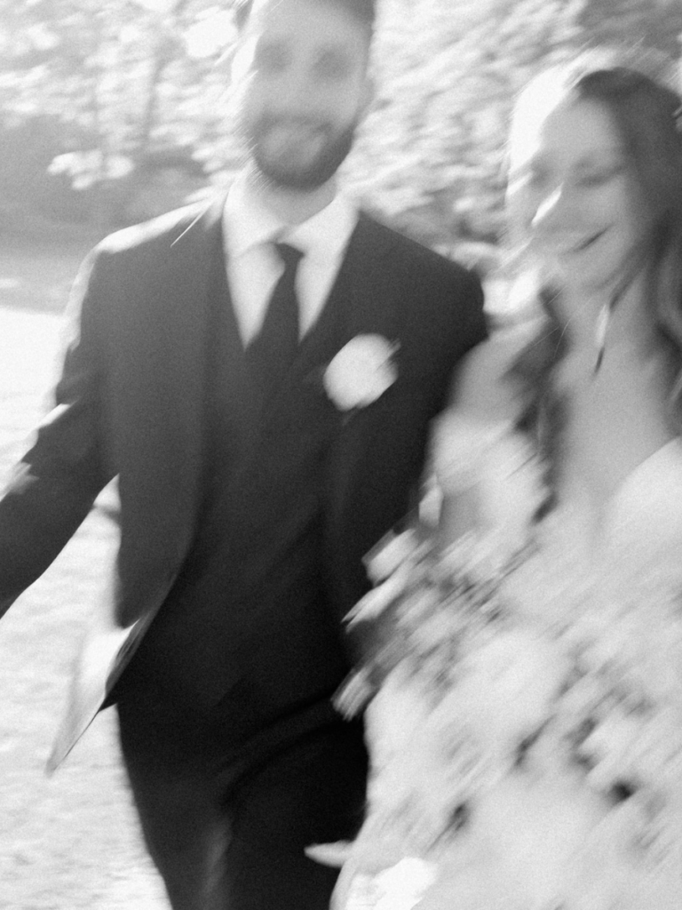 Blurry black & white photo of the couple smiling and walking