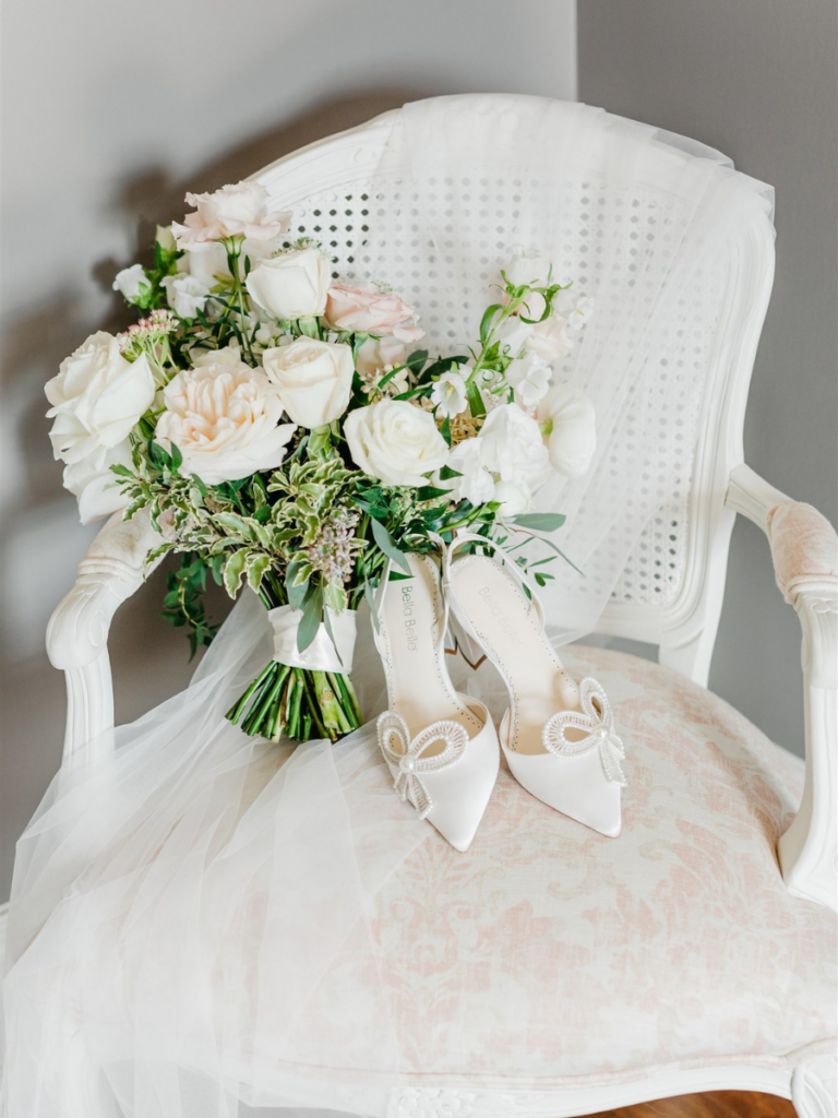 Bridal veil draped over a chair with bridal bouquet and shows resting on the chair