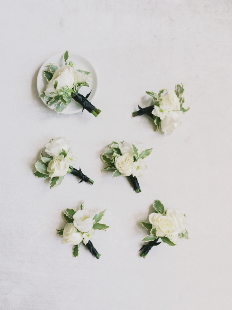 Groomsmen and groom boutonnieres with white florals and greenery