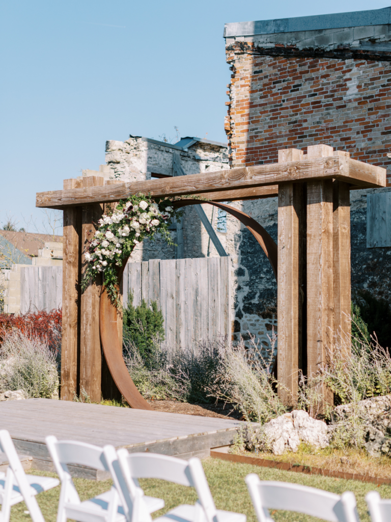 Outdoor ceremony at the Elora Mill with floral arrangements on the arbour 