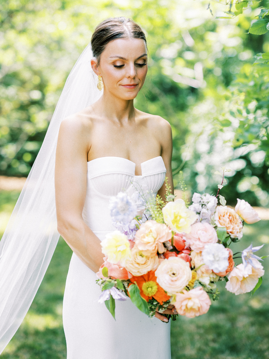 Bride holding her colourful flower bridal bouquet. Used in the bouquet were poppies, peonies, ranunculus, tulips, garden roses, sweet pea, scabiosa, and clematis.